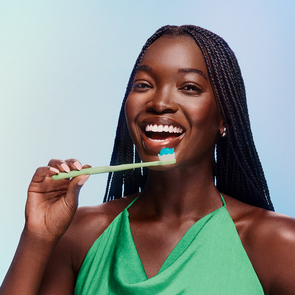 Woman holding a toothbrush with a blue background