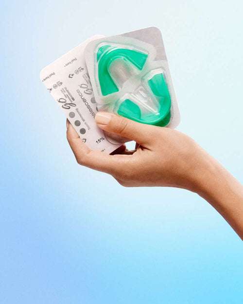 Hand holding Opalescence Go prefilled whitening trays still in their packaging