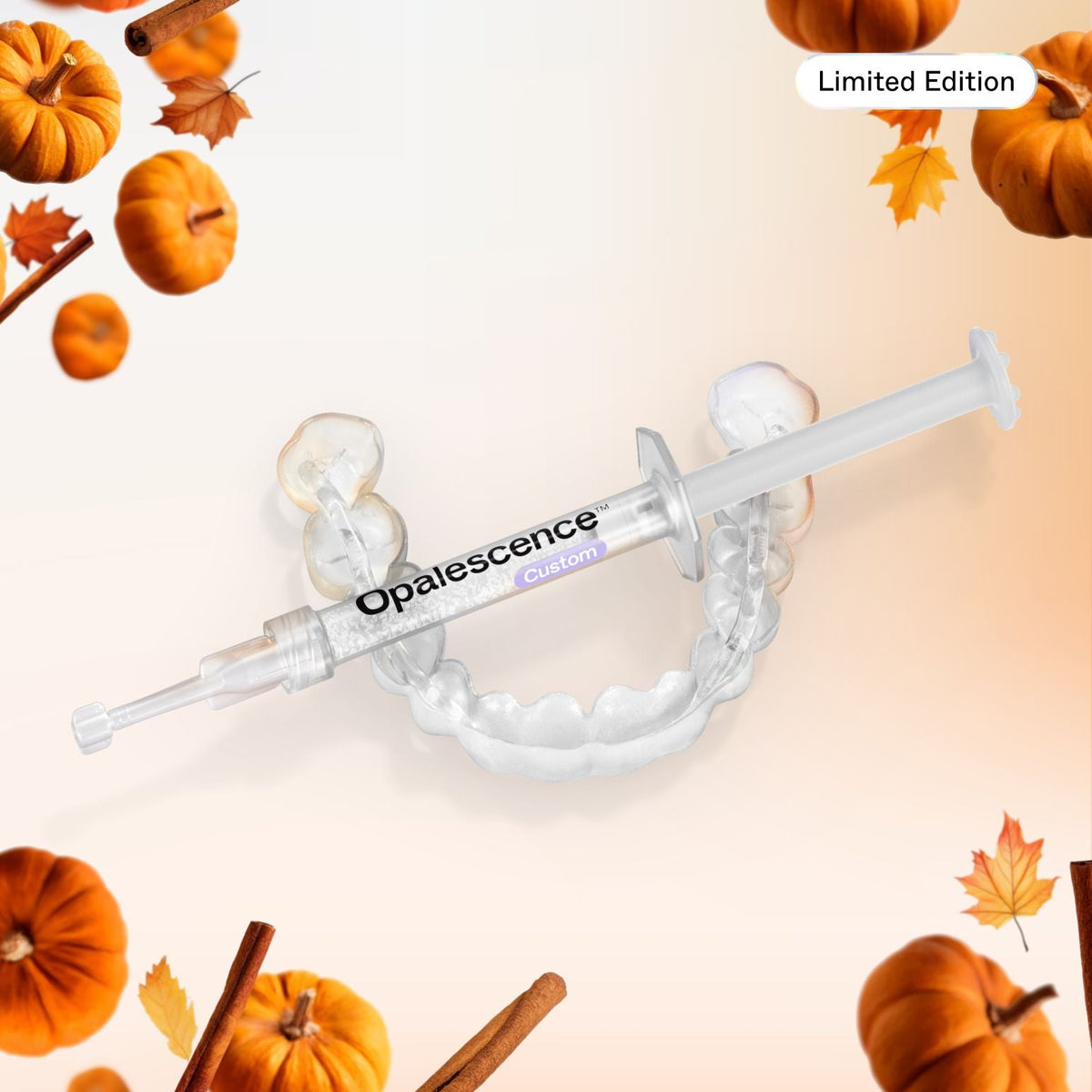 A clear dental impression tray with a syringe-style applicator printed with the brand name Opalescence, shown on a pale peach background with decorative autumn pumpkins, leaves, and cinnamon sticks. A small 'Limited Edition' badge appears in the top right.
