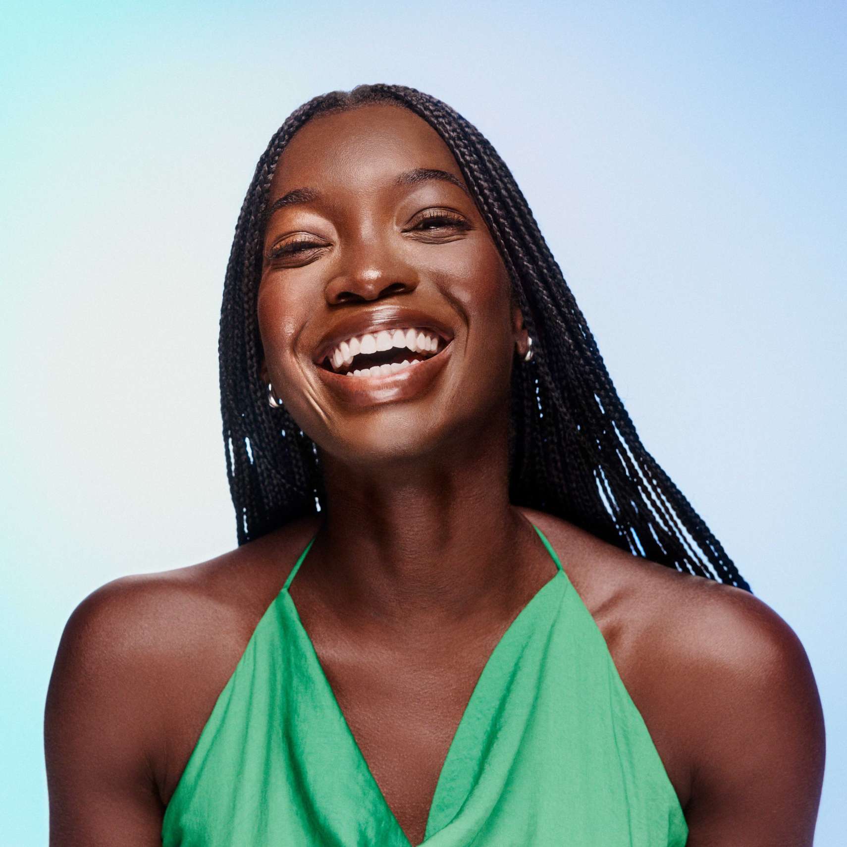 Woman with a bright smile and long braided hair wearing a green halter top