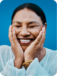 Smiling woman with her eyes closed and her hands on face under her chin