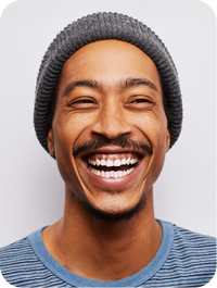 Man with a big smile wearing a gray beanie and blue striped shirt 