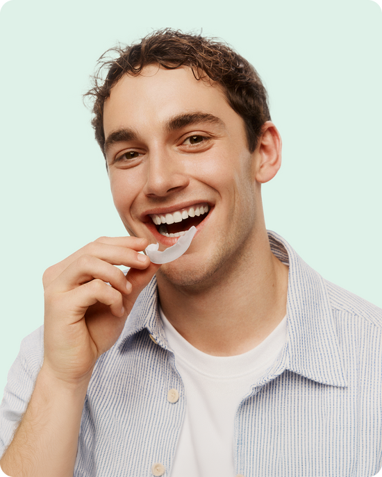 Smiling man placing the Opalescence Go tray on teeth.