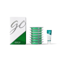 Green dental floss containers with a box labeled 'GO' on a white background and a travel size tube of toothpaste 