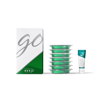 Green dental floss containers with a box labeled 'GO' on a white background and a travel size tube of toothpaste 