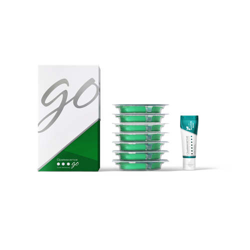 Green dental floss containers with a box labeled 'GO' on a white background and a travel size tube of toothpaste 